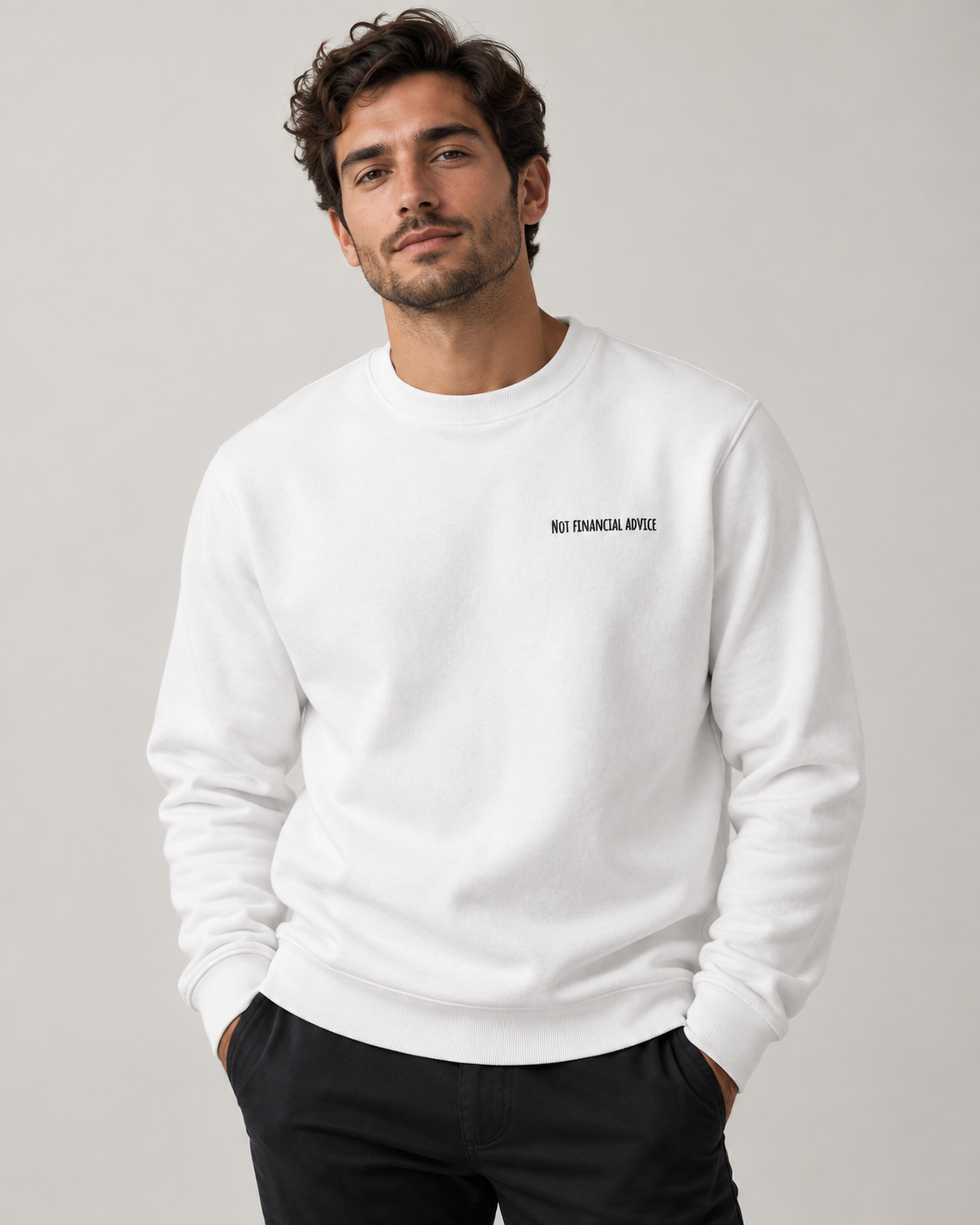 Man wearing a white Not Financial Advice sweatshirt with black left-chest embroidery, photographed in a neutral studio.